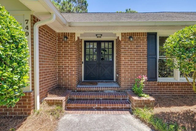 property entrance featuring french doors and brick siding