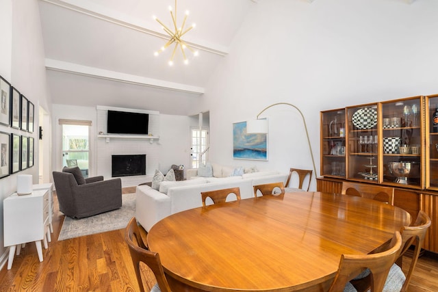 dining room with a healthy amount of sunlight, an inviting chandelier, a brick fireplace, and wood finished floors