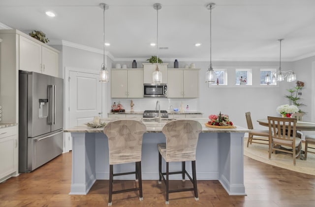 kitchen with stainless steel appliances, an island with sink, dark hardwood / wood-style flooring, and decorative light fixtures