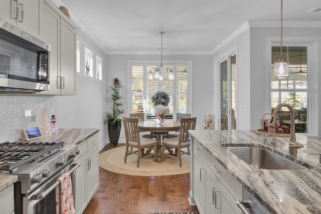 kitchen with dark wood-type flooring, sink, decorative light fixtures, appliances with stainless steel finishes, and light stone countertops