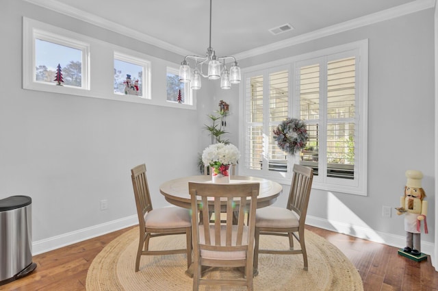 dining room with hardwood / wood-style floors, crown molding, and a chandelier