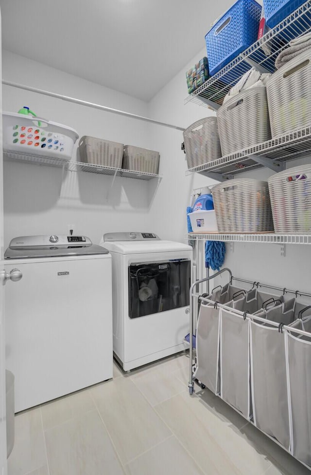 clothes washing area with washing machine and dryer and light tile patterned floors