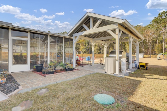 view of yard featuring a gazebo, a patio area, a sunroom, and exterior kitchen