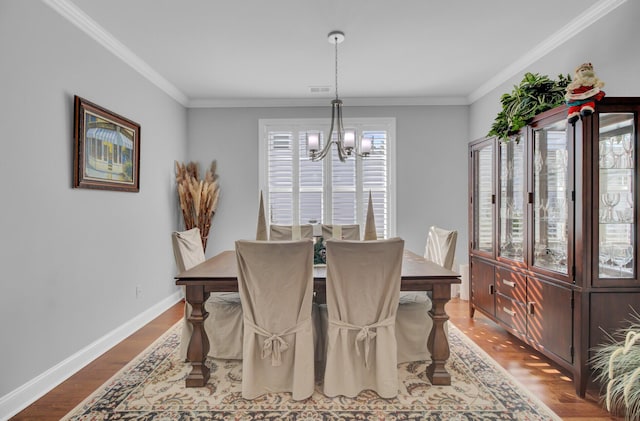 dining area featuring crown molding, hardwood / wood-style floors, and a notable chandelier