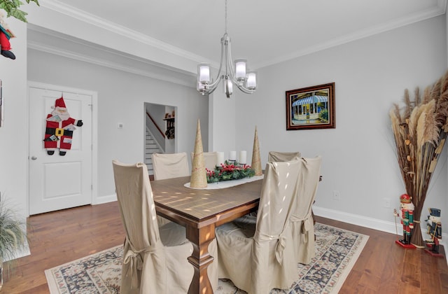 dining space with dark wood-type flooring, ornamental molding, and an inviting chandelier