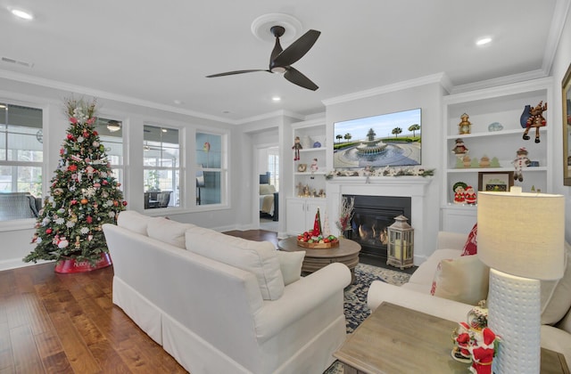 living room featuring ornamental molding, dark wood-type flooring, built in features, and ceiling fan