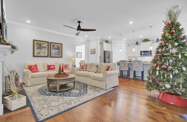 living room with ornamental molding, light hardwood / wood-style floors, and ceiling fan