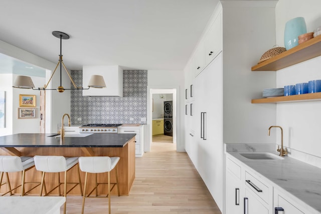 kitchen with a breakfast bar area, sink, light wood-type flooring, and white cabinets