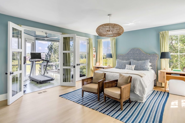 bedroom featuring french doors, access to exterior, wood-type flooring, and multiple windows