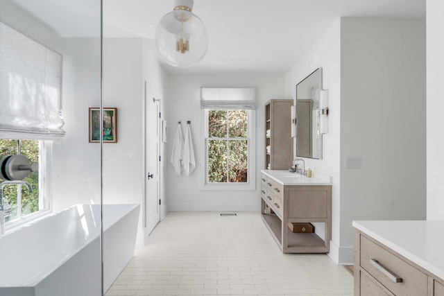 bathroom with a tub to relax in, vanity, and tile patterned flooring