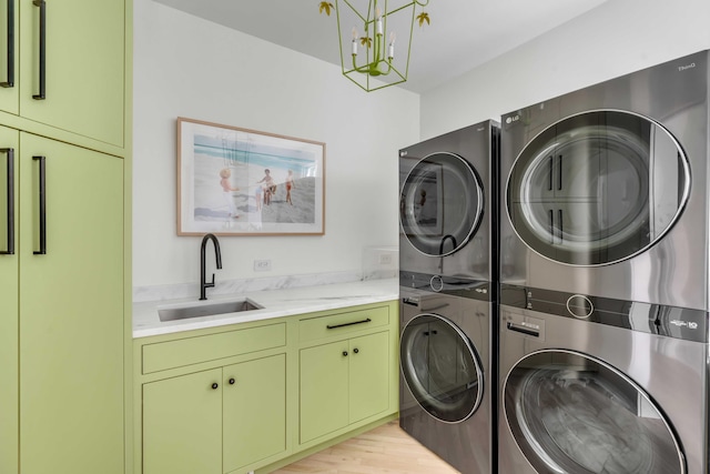 laundry room featuring light hardwood / wood-style flooring, cabinets, stacked washer / drying machine, and sink