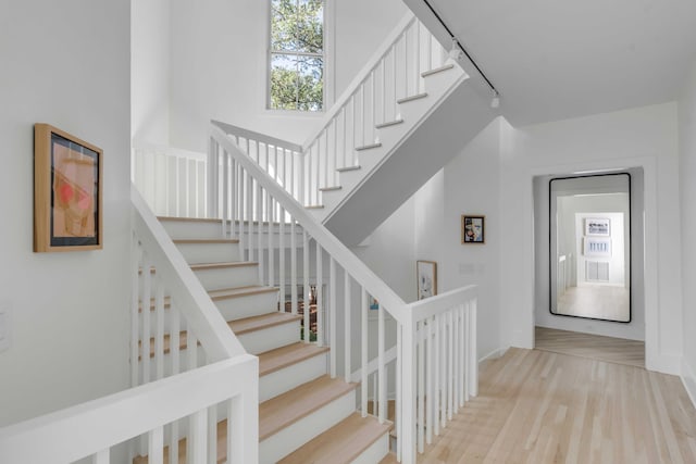 staircase featuring rail lighting and hardwood / wood-style flooring