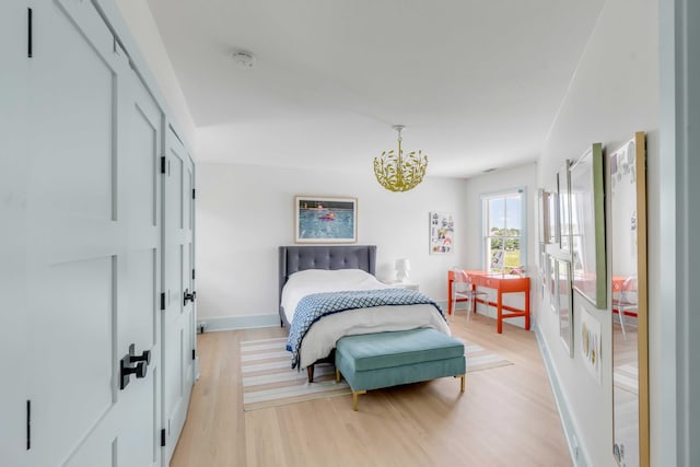 bedroom with a notable chandelier and light wood-type flooring