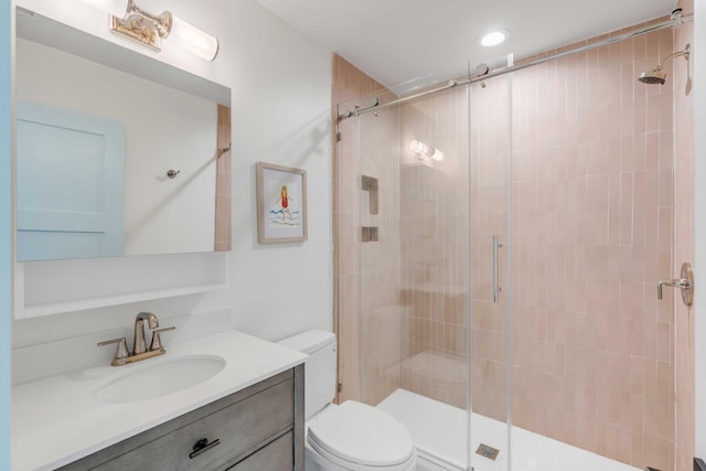 bathroom featuring a shower with door, vanity, and toilet