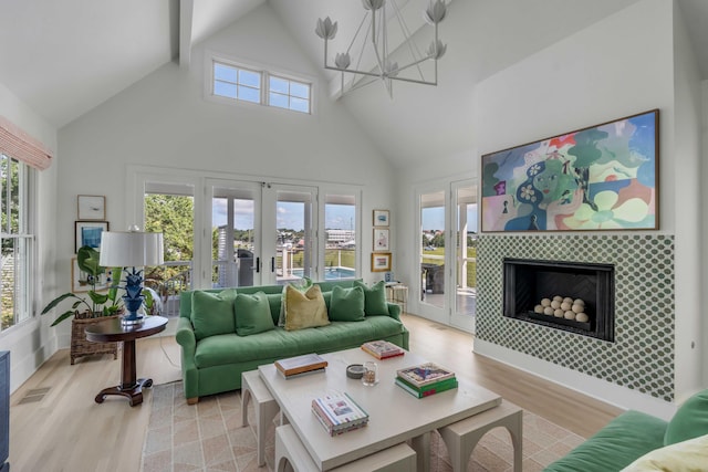 living room featuring a fireplace, high vaulted ceiling, a healthy amount of sunlight, and light hardwood / wood-style floors