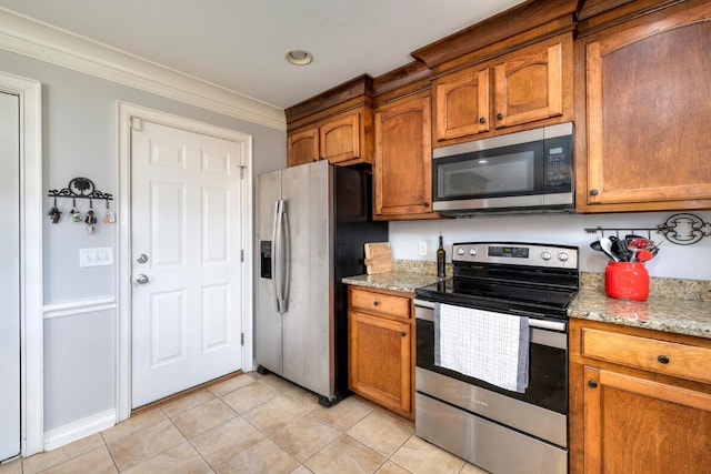 kitchen with light tile patterned floors, appliances with stainless steel finishes, ornamental molding, and brown cabinets