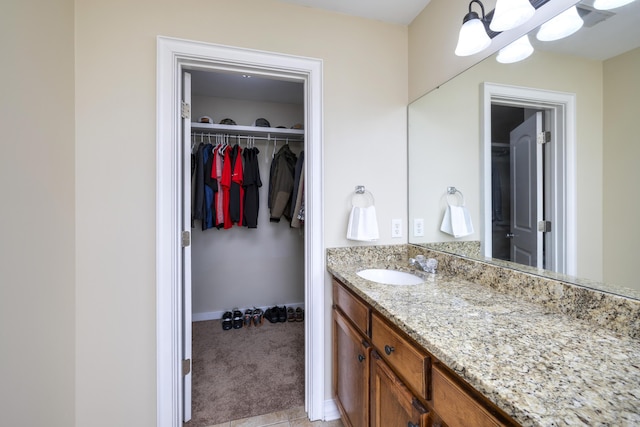 bathroom featuring vanity, baseboards, and a walk in closet