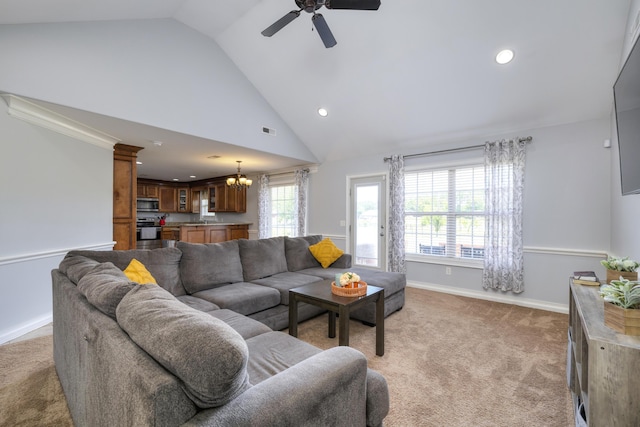 living area with light carpet, high vaulted ceiling, ceiling fan with notable chandelier, recessed lighting, and baseboards