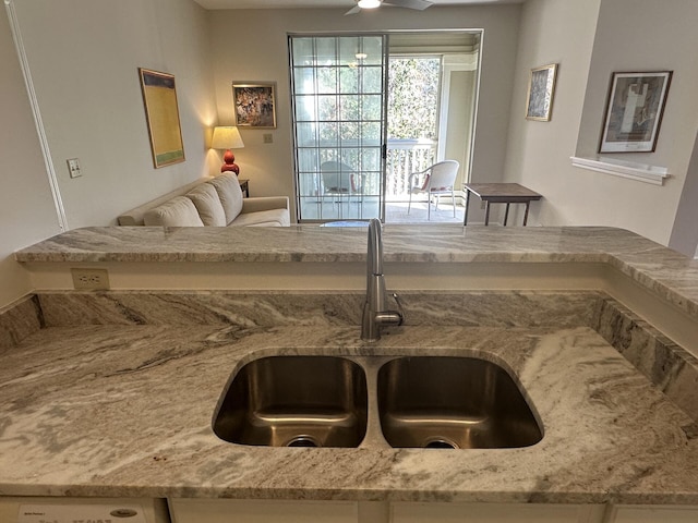 interior space with light stone countertops, sink, and ceiling fan