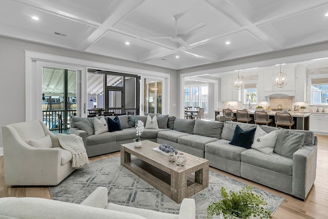 living room featuring beam ceiling, recessed lighting, light wood-style flooring, an inviting chandelier, and coffered ceiling