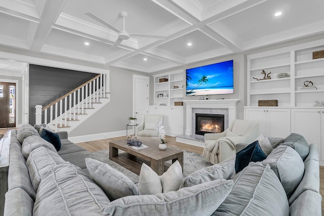 living area with stairs, beamed ceiling, coffered ceiling, and a fireplace