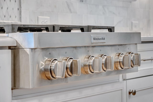 room details with stove, tasteful backsplash, and white cabinets