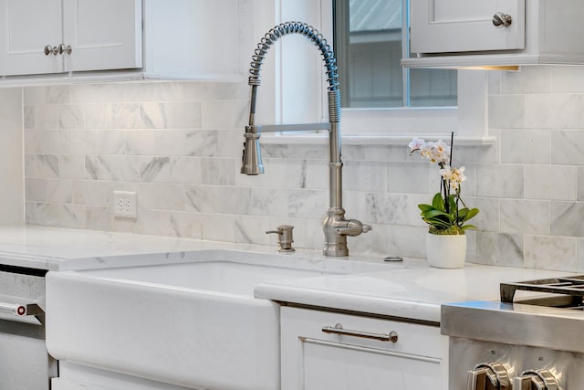 interior details featuring light stone counters, white cabinets, and a sink