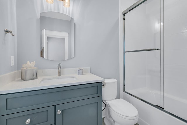 bathroom with combined bath / shower with glass door, toilet, and vanity