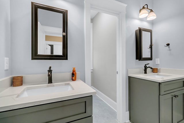 bathroom with a sink, baseboards, two vanities, and tile patterned flooring