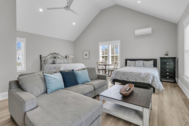 bedroom featuring a ceiling fan, baseboards, high vaulted ceiling, a wall mounted air conditioner, and light wood-type flooring