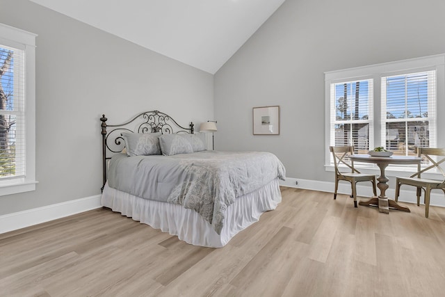 bedroom with high vaulted ceiling, light wood-type flooring, and baseboards