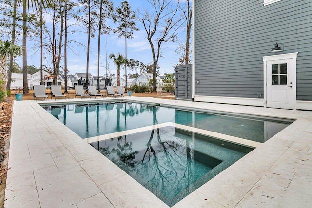 view of pool featuring a residential view, a pool with connected hot tub, a patio, and fence