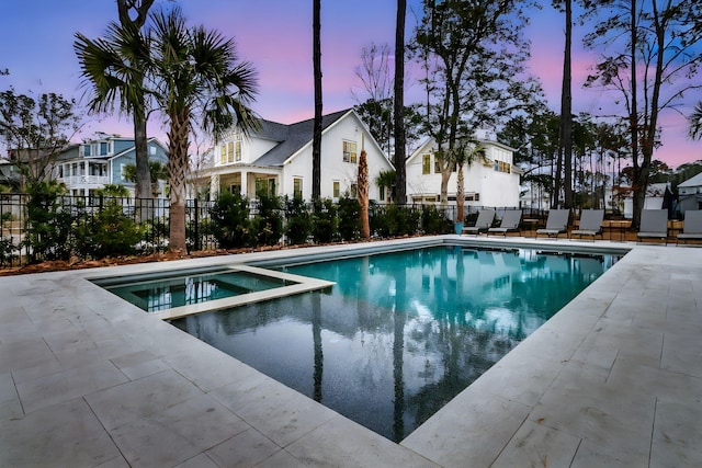 view of swimming pool with a patio area, a pool with connected hot tub, and fence