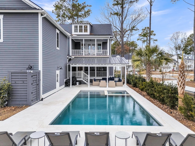 back of property featuring an outdoor living space, a pool with connected hot tub, stairway, a balcony, and a patio area