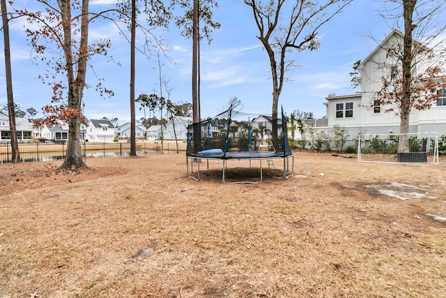 view of yard with a residential view, a trampoline, and fence