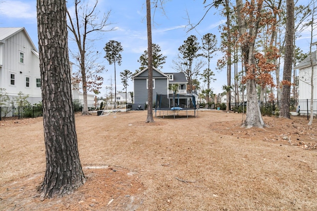 view of yard featuring a trampoline and fence