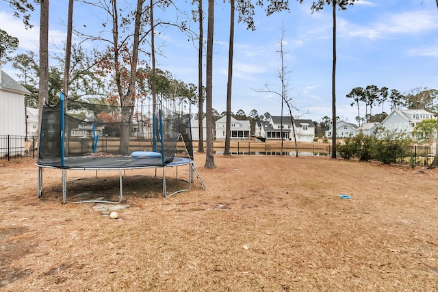 view of yard with a residential view, a trampoline, and fence