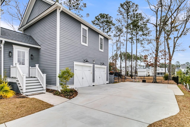 view of home's exterior with driveway, an attached garage, and fence