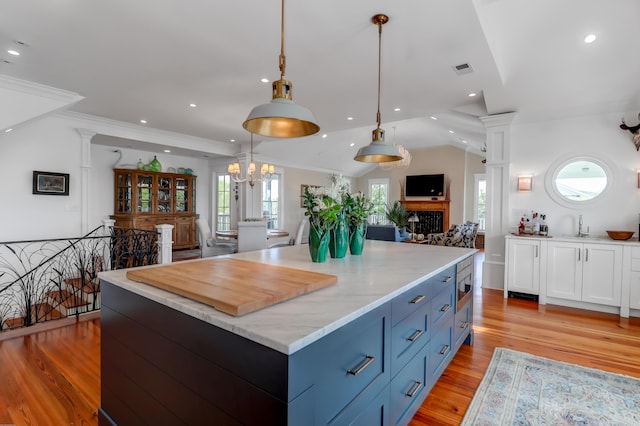 932 Middle St, Sullivans Island, SC 29482 - kitchen with open floor plan, blue cabinetry, light wood-style floors, a chandelier, and hanging light fixtures
