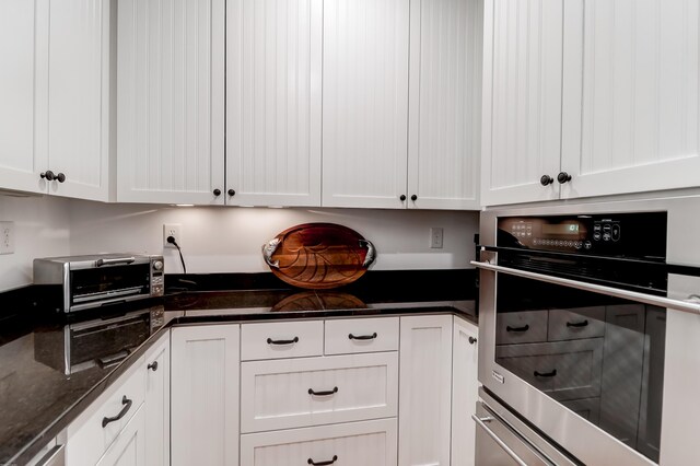 932 Middle St, Sullivans Island, SC 29482 - kitchen with stainless steel oven, white cabinetry, and dark stone counters