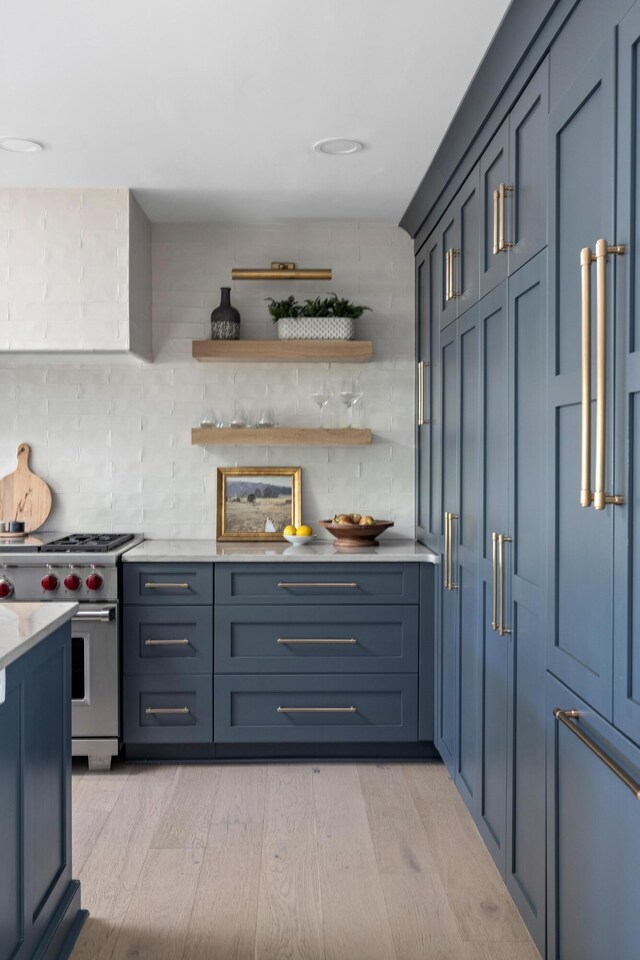 bar featuring decorative backsplash, stainless steel stove, and light wood finished floors