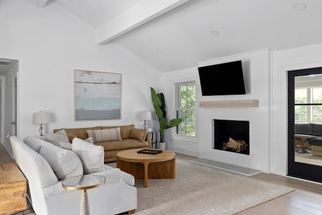 living area with lofted ceiling with beams, a healthy amount of sunlight, a fireplace with flush hearth, and wood finished floors