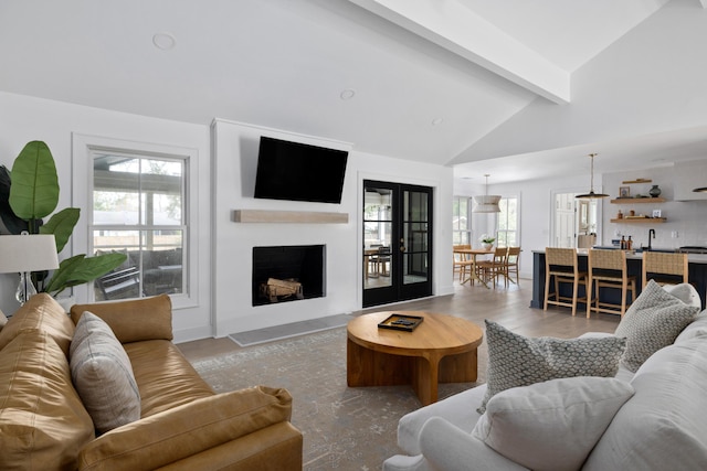 living area with lofted ceiling with beams, a fireplace, and french doors