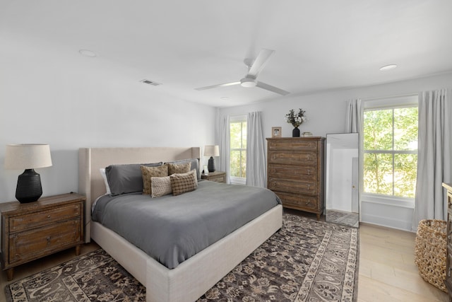 bedroom featuring light wood-style floors, visible vents, ceiling fan, and multiple windows