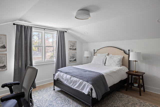 bedroom featuring lofted ceiling, light wood finished floors, and baseboards