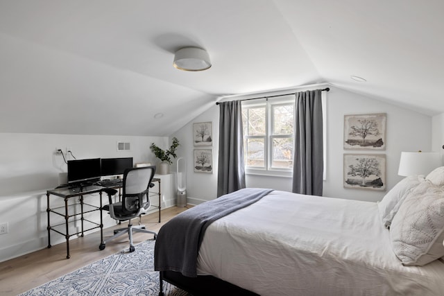 bedroom with lofted ceiling, visible vents, baseboards, and wood finished floors