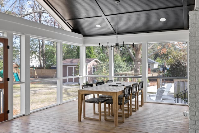 sunroom with a healthy amount of sunlight, a chandelier, and vaulted ceiling