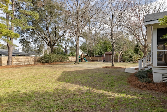 view of yard featuring a playground, an outdoor structure, a storage shed, and fence