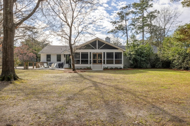 back of house featuring a sunroom, a yard, a chimney, and a patio