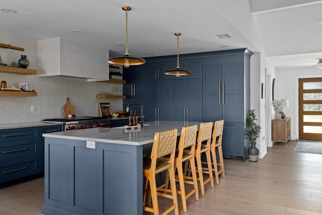 kitchen featuring custom range hood, light wood-type flooring, blue cabinetry, open shelves, and a sink